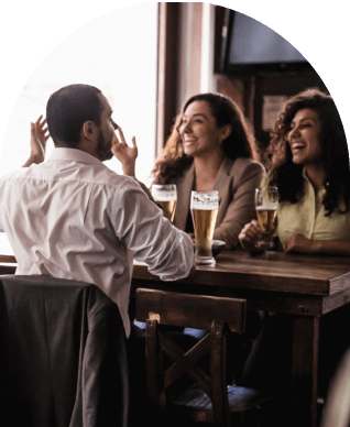 Tres personas riendo mientras toman cerveza en un bar